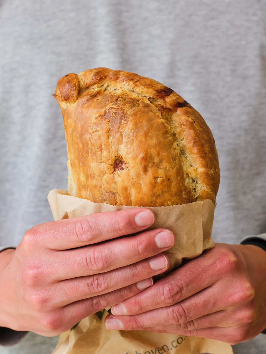 The Cornish Oven Flaky Pasty In Hand Grey Background